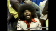 a man with an afro is sitting at a piano