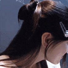 a woman with a clip in her hair stands in front of a blackboard with the letter p.o.l. written on it
