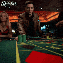 a man is holding stacks of green poker chips in front of a sign that says rainbet on it