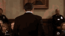a man in a suit is standing in front of a crowd of people in a courtroom .
