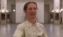 a woman in a white shirt is making a funny face in a room .