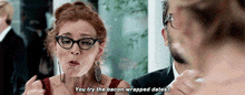 a woman wearing glasses is talking to a man and says " you try the bacon-wrapped dates "