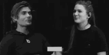 a black and white photo of a man and a woman talking to each other .