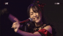 a woman singing into a microphone with the words live on the bottom right