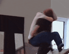 a man is carrying another man in his arms in front of a window