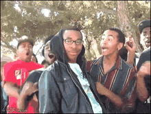 a man in a hooded jacket is surrounded by a crowd of people with a 4gifs.com watermark on the bottom