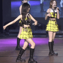 a girl in a plaid skirt is holding a microphone on stage