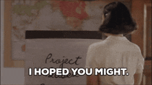 a woman says i hoped you might while standing in front of a project board