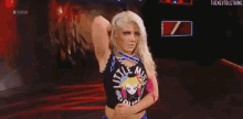 a woman in a wrestling outfit is standing on a stage with her arm around her waist .