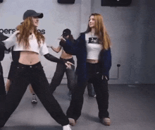 a group of young women are dancing in a room with the word personas on the wall behind them