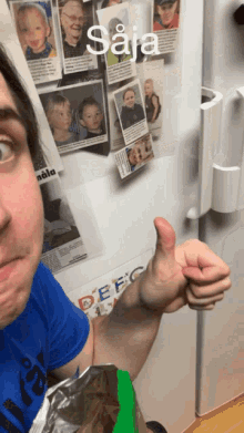 a man giving a thumbs up in front of a fridge that has a picture of a boy on it