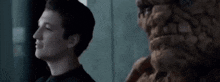 a man with a fireball in his mouth is looking at a statue of a man .