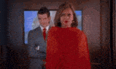 a woman wearing red high heels is walking down a hallway with a red purse .