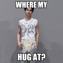 a man in a white shirt stands in front of a wall with a meme that says " where my hug at "