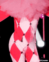 a woman in a pink and white harlequin costume is dancing