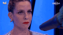 a woman 's face is being blow dried by a hair dryer with the tvi logo in the background