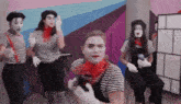 a group of people dressed as mimes are dancing and making funny faces .