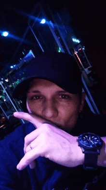 a man wearing a black hat and a watch is making a silly face