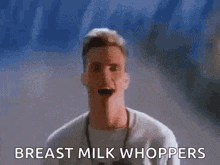 a man is standing in front of a blue and yellow wall with the words `` breast milk whoppers '' written on it .