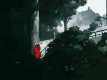 a person in a red robe is standing on a sidewalk in the woods .