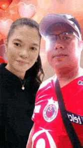 a man and a woman are posing for a picture and the man is wearing a red shirt that says ' a '