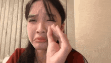 a woman is making a funny face while holding her face with her hand .