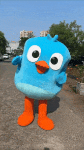 a blue bird mascot is standing on the sidewalk
