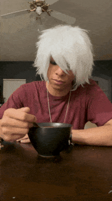 a person with white hair is sitting at a table with a cup of coffee