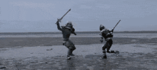 two soldiers are standing in the water holding swords