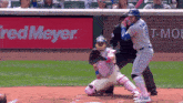 a baseball player swings his bat at a ball in front of a red meyer sign