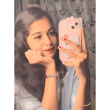 a girl taking a picture of herself with a hello kitty case