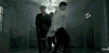 a group of men are standing in a dark room with a chandelier and a sign that says 1the .