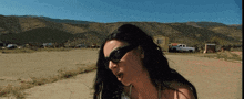 a woman wearing sunglasses is standing in a field
