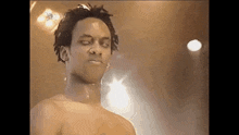 a shirtless man with dreadlocks and a nose ring is standing in front of a stage .