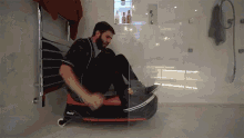 a man is sitting on a razor sled in a bathroom