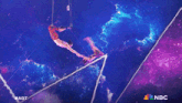 a gymnast performs a trick on a purple background with the nbc logo in the corner