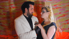 a man in a white suit is holding a woman 's hand