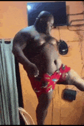 a man without a shirt is dancing in a room with a television .