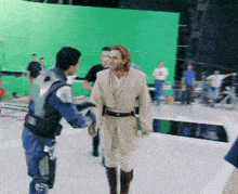 a man in a star wars costume shakes hands with another man in a blue vest
