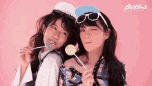 two young women are holding lollipops in their mouths .