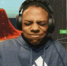 a man wearing headphones and a blue hoodie is looking down