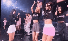a group of women are dancing on a stage in front of a large screen .