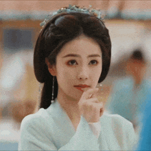 a woman with a crown on her head is making a funny face .