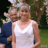 a woman in a white wedding dress is standing in front of a man in a blue suit ..