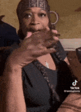a woman wearing a headband is smoking a cigarette and making a face .