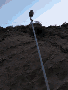 a street light is hanging from a pole near a cliff