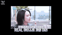 a woman wearing sunglasses and a black jacket is sitting in front of a window with a caption that says real