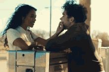 a man and a woman are looking at each other and the man is touching the woman 's face