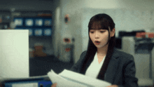 a woman in a suit holds a piece of paper in her hands
