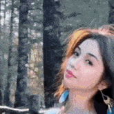 a close up of a woman 's face in front of a forest